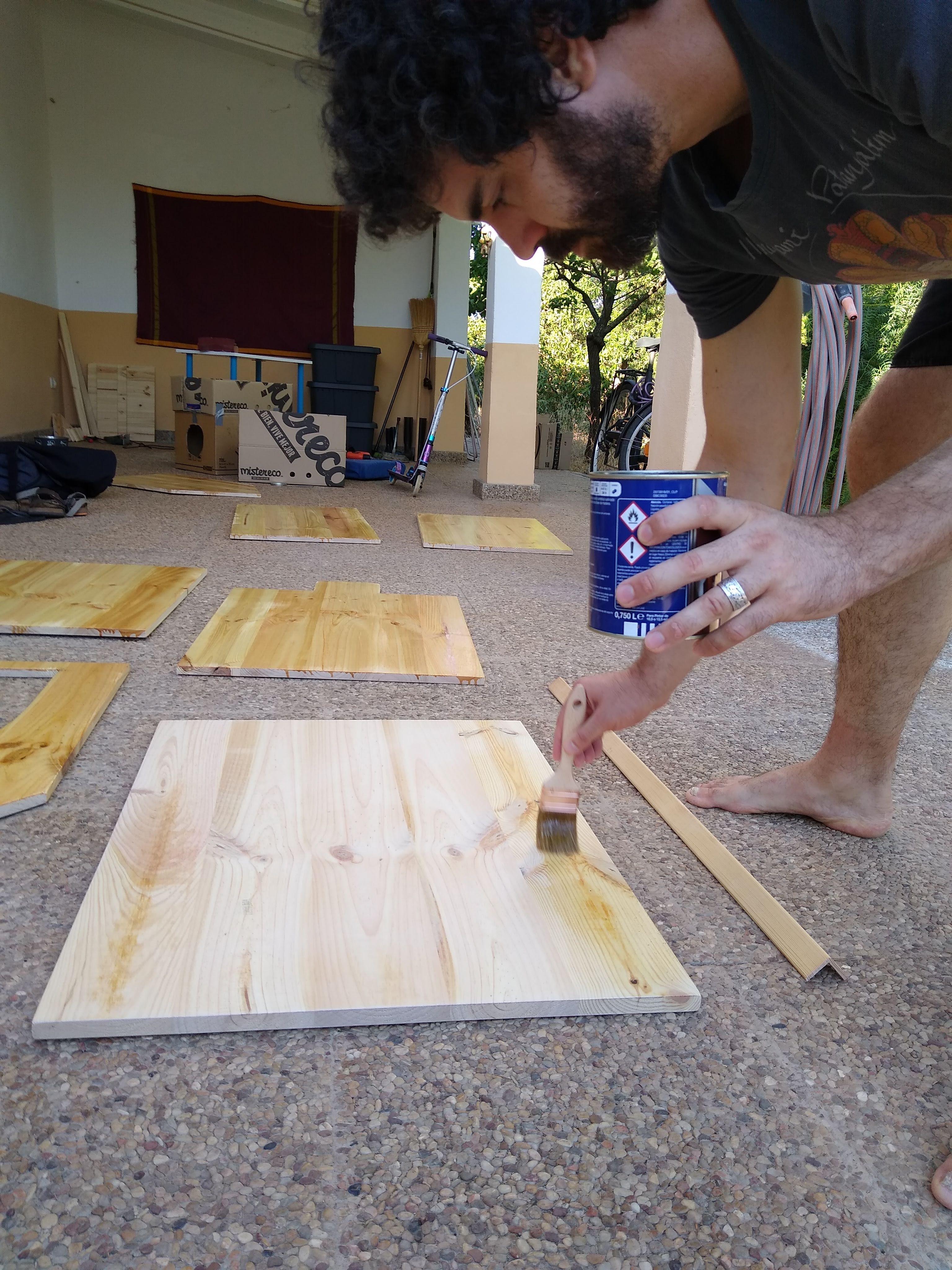 Persona aplicando barniz con brocha sobre una superficie de madera