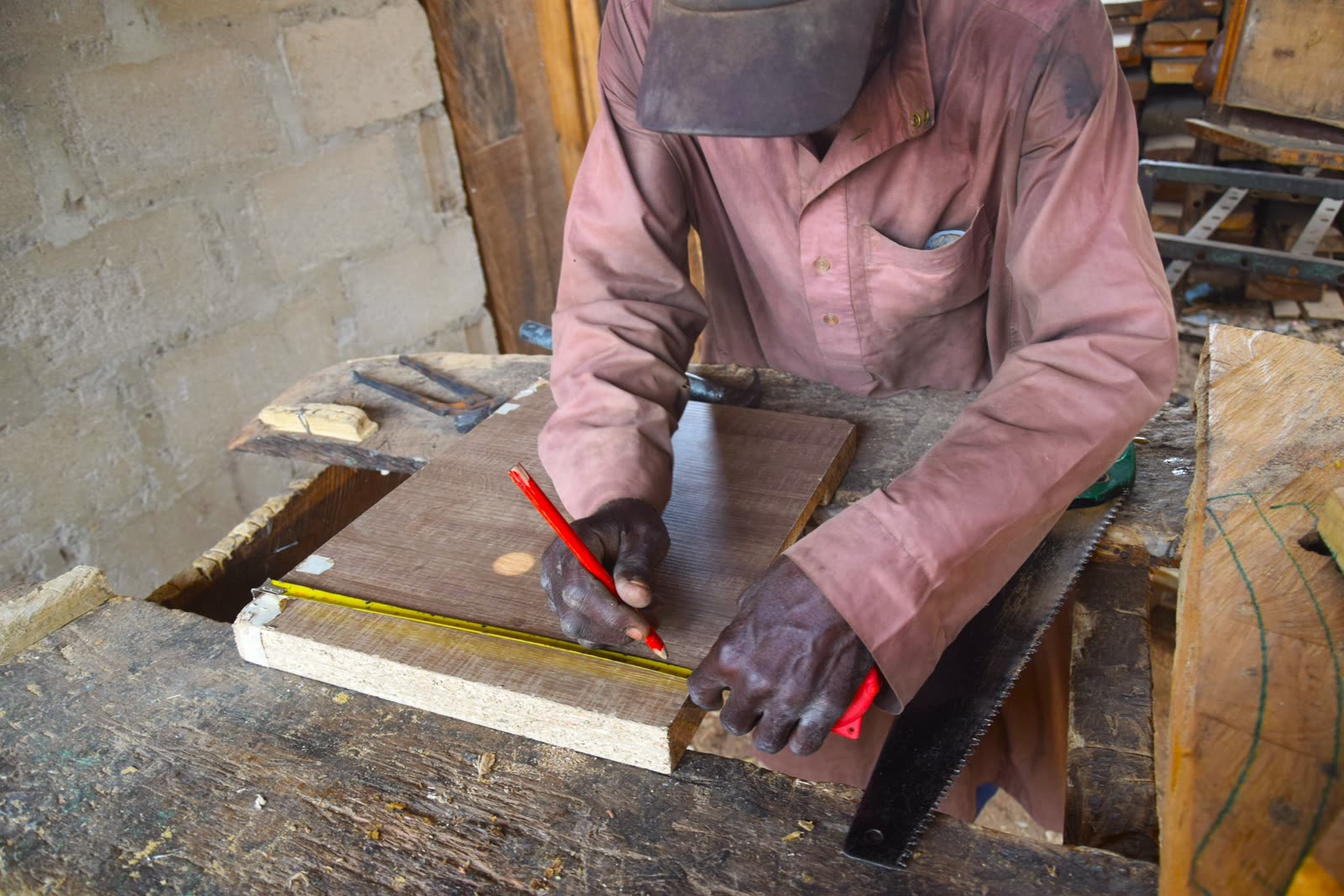 Carpintero midiendo y trabajando una pieza de madera en su taller