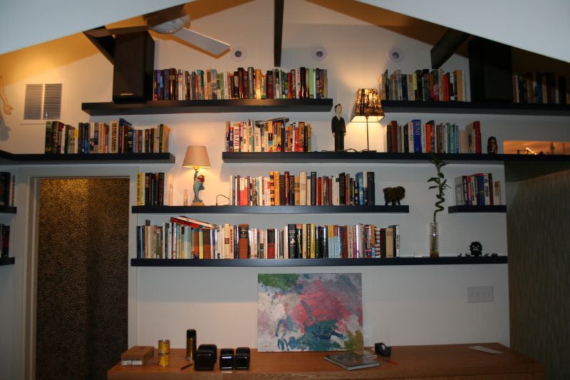 Estanterías flotantes de madera montadas en pared, sin soportes visibles, llenas de libros