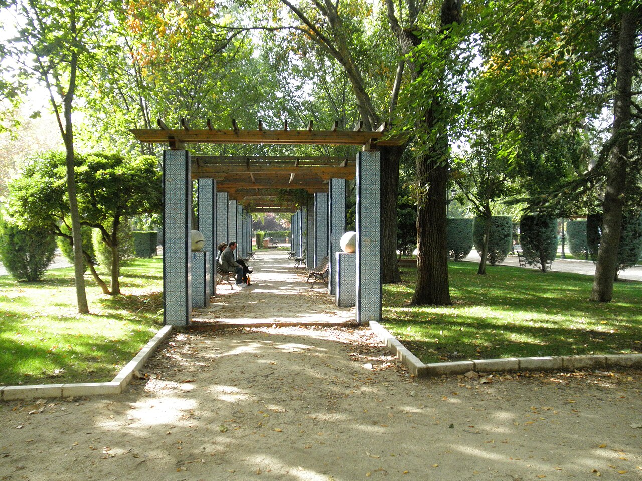Pérgola de madera en un jardín con vigas y celosía de sombra
